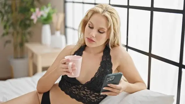 Avslappnad kvinna i spetsunderkläder skickar sexiga meddelanden i gratis sexchatt via mobilen – sexdate på distans.