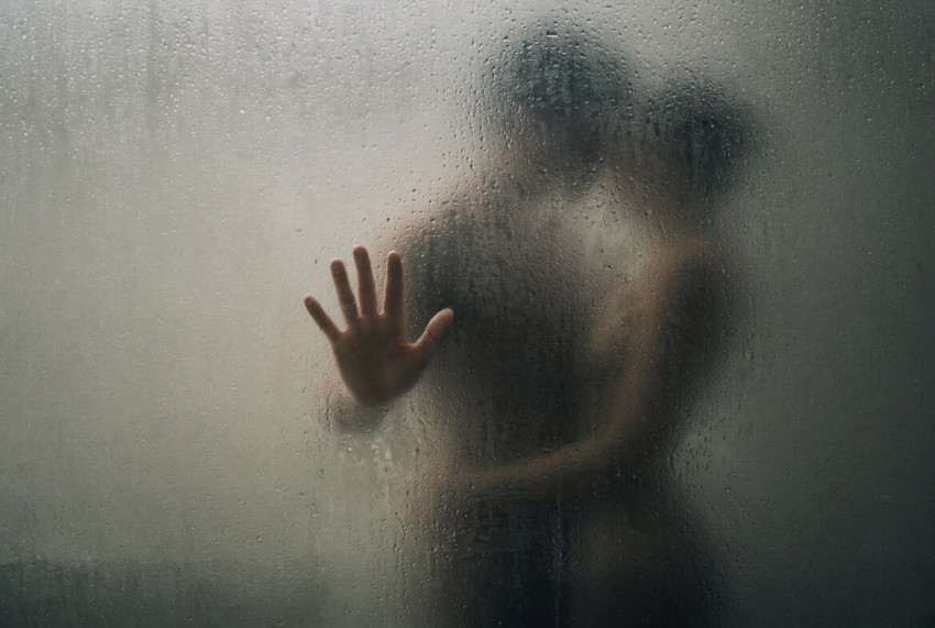 Silhuetter av nakna kroppar bakom immat duschglas, hand tryckt mot glaset &ndash; Sexdejting Sverige