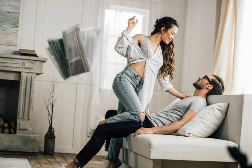 Lyckligt par leker i soffan med flygande tidningar &ndash; illustration av sp&auml;nningen vid gift s&ouml;ker gift och diskret v&auml;nsterprassel utan drama.